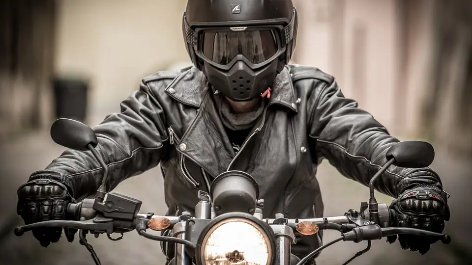 Motociclista com capacete pilotando em via pública