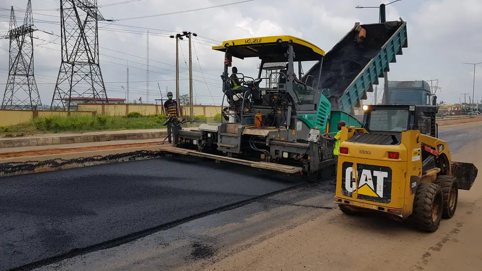 Trabalhadores aplicando asfalto em via pública