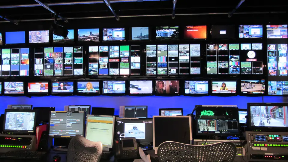 Sala de controle de transmissão de TV com telas e consoles