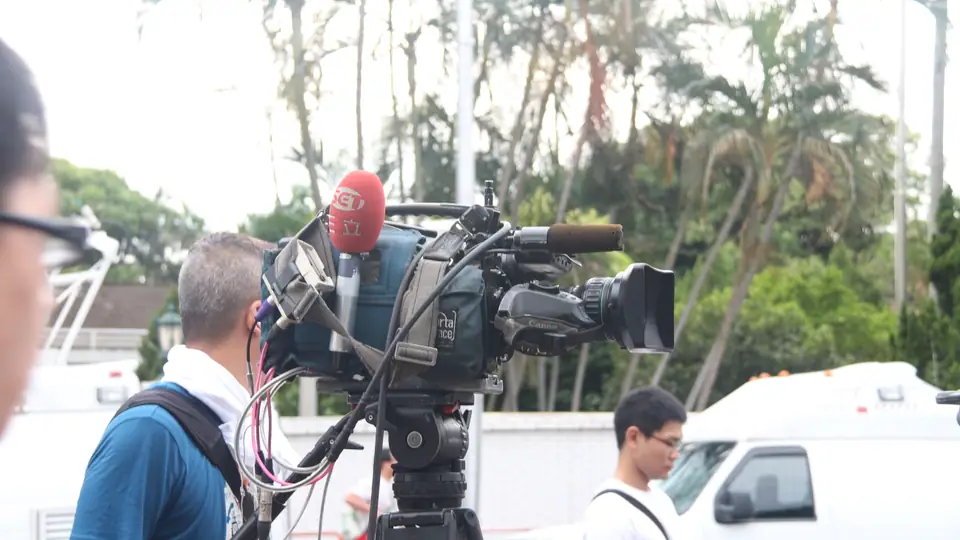 Câmera de televisão profissional sobre tripé em sala de transmissão